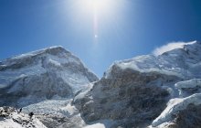 Montañas cubiertas de nieve y sol brillante en el cielo azul - foto de stock