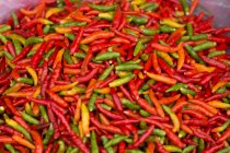 Close-up of pile of red, yellow and green chili peppers — Stock Photo