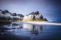 Meereswellen am Strand unter schneebedeckten Bergen, Island, Europa — Stockfoto