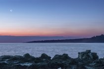 Восход солнца над скалой на живописном пляже — стоковое фото