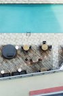 Vista de ángulo alto de las mesas en la piscina del hotel - foto de stock