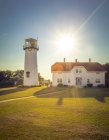 House and lighthouse on rural lawn in backlit — Stock Photo