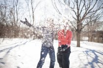 Молодая пара бросает снежки в зимний парк — стоковое фото
