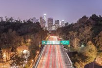 Los Angeles city skyline over busy highway illuminated at night, California, United States — Stock Photo