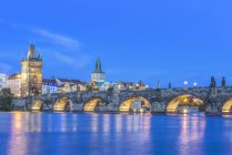 Puente de Carlos y ciudad iluminada al atardecer, Praga, República Checa - foto de stock