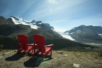 Red lawn chairs near scenic mountain landscape — Stock Photo
