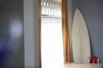 Still life of surfboard and table at window indoors in Seattle, USA — Stock Photo