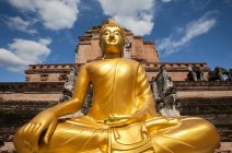 Низкоугольный вид на золотую статую Будды снаружи, Чианг Мбай, Чианг Мбай, Таиланд — стоковое фото