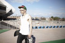 Homme caucasien portant skateboard près du stade — Photo de stock