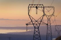 Silhouette delle linee elettriche e pilone al tramonto — Foto stock
