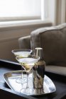 Deux cocktails garnis dans des verres avec shaker sur plateau dans le salon moderne — Photo de stock