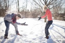 Jeune couple ayant combat de boule de neige dans le parc d'hiver — Photo de stock