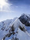 Tapas de montaña cubiertas de nieve bajo luz solar brillante - foto de stock