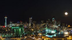 Seattle skyline lit up at night under full moon in sky, Washington, USA — Stock Photo