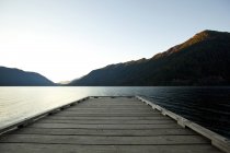 Cubierta de madera en el lago bajo el cielo azul - foto de stock