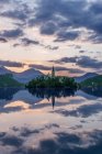 Village church and buildings reflected in still lake, Bled, Upper Carniola, Slovenia — Stock Photo