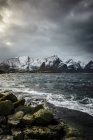 Snowy mountains overlooking rocky coastline, Reine, Lofoten Islands, Norway — Stock Photo