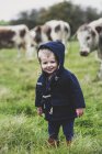 Young boy standing on pasture with English Longhorn cows in background. — Stock Photo