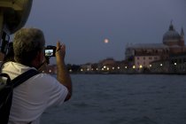 Rear view of male tourist taking picture of Canale Grande in Venice, Veneto, Italy at night. — Stock Photo