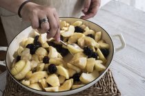 Close-up of hands of woman placing apples and blackberries in round baking tin. — Stock Photo