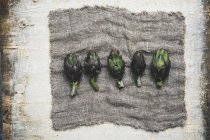 Vista en ángulo alto de alcachofas frescas sobre tela gris . - foto de stock