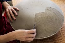 Gros plan d'un artiste céramique travaillant sur un bol en argile, appliquant un motif avec un outil à main . — Photo de stock