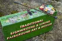 High angle view of painting materials on green metal toolbox of traditional sign-writer. — Stock Photo