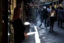 Местная женщина, стоящая на узкой улице в Венеции, Венето, Италия и курящая сигарету . — стоковое фото