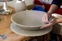 Nahaufnahme eines Keramikkünstlers in einer Werkstatt, der an einer Tonschale arbeitet. — Stockfoto