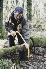 Hombre parado en el bosque y cortando árboles con sierra de arco . - foto de stock