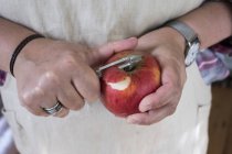Close-up de pessoa descascando maçã vermelha com descascador de lâmina dupla . — Fotografia de Stock