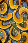 High angle view of slices of pumpkin with seeds on baking tray. — Stock Photo
