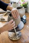 Close-up de artista cerâmico trabalhando em vaso de argila usando ferramenta de cerâmica . — Fotografia de Stock