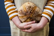 Gros plan de la personne tenant une miche ronde de pain fraîchement cuite . — Photo de stock