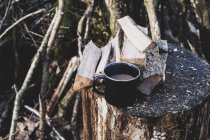 High angle view of mug of tea and wooden logs on chopping block. — Stock Photo