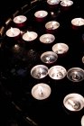 High angle close-up of lit tea light candles on tray in church. — Stock Photo
