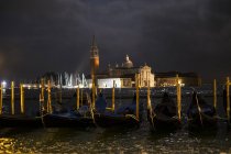 Illuminated gondolas moored in Canale Grande in Venice, Italy, at night and view across water lagoon — Stock Photo