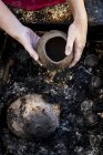 Primo piano di artista ceramica seduto accanto alla fossa del fuoco fumo all'aperto, che lavora su vaso . — Foto stock
