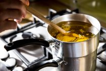 Close up of person melting wax for candle in saucepan on stove. — Stock Photo
