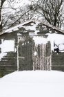 Vista exterior del cobertizo de jardín de madera gris con ventanas cubiertas de nieve . - foto de stock
