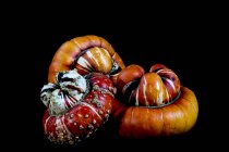 Close-up of three orange and red Turban pumpkins on black background. — Stock Photo