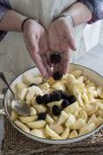 Крупним планом жінки розміщення яблук скибочками і ожини в круглої випічки олова. — стокове фото