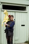 Femme portant le traditionnel cheval galoper carrousel peint en bois de manège sur l'épaule à l'extérieur de l'atelier — Photo de stock