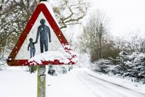 Primer plano de los peatones en la señal de tráfico al lado de la carretera rural cubierta de nieve . - foto de stock