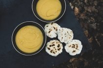 High angle close-up of freshly made bread buns and bowls of soup over campfire. — Stock Photo