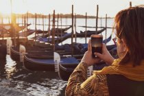 Nahaufnahme einer Frau beim Fotografieren von Gondeln, die in canale grande in Venedig, Venetien, Italien vertäut sind. — Stockfoto