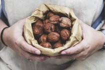 Close up of person holding brown paper bag with fresh walnuts. — Stock Photo