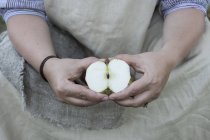 Primer plano de la mujer sosteniendo manzana cortada por la mitad . - foto de stock