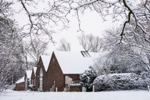 Exterior view of red brick cottages with snow-covered roofs along rural road. — Stock Photo