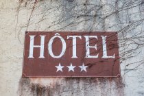 Крупним планом 3-зірковий готель знак на сірому стіні з голими гілки дерев. — стокове фото